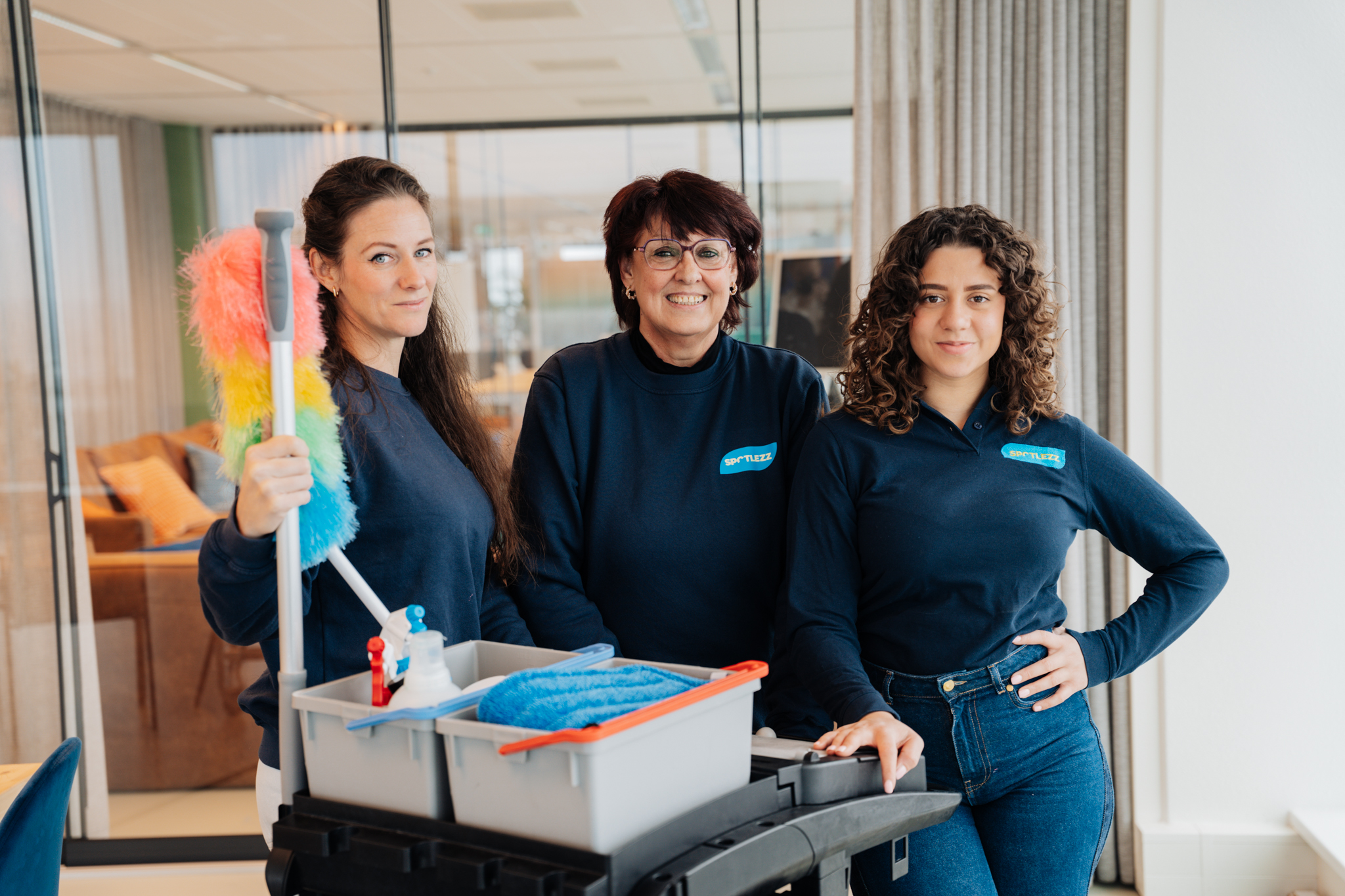 Het schoonmaakteam van Spotlezz met een werkwagen op kantoor